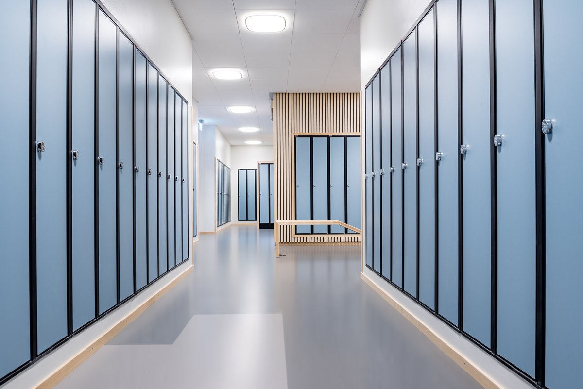 Bilde som viser gangen på en skole, hvor det er plassert flotte, lyseblå elevskap langs veggene. Skapene har laminatdører og solide hasper for hengelås.