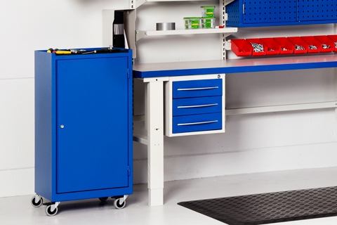 En blå verkstedbenk med en enkel dør, står ved siden va et justerbart arbeidsbord.